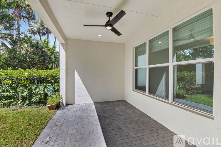 A patio area with a ceiling fan and brick flooring.