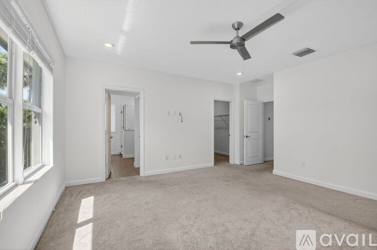 A spacious room with a ceiling fan and carpeted floor.