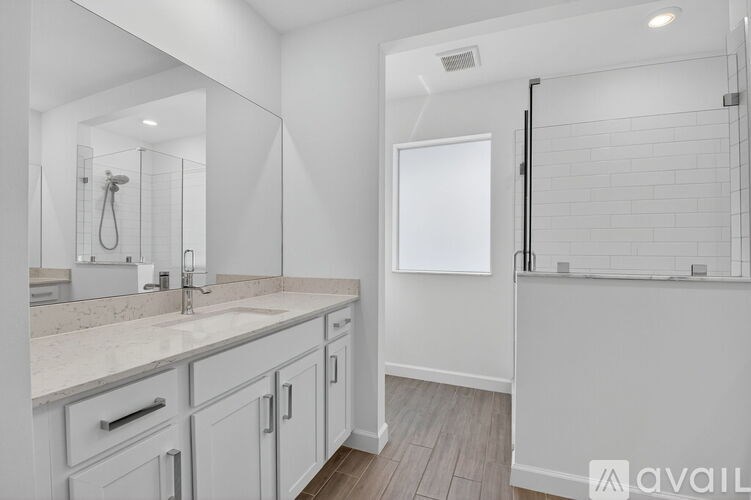 A bathroom with a marble countertop and white cabinets.