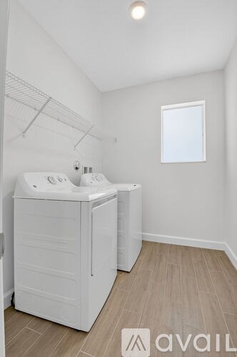 A white bathroom with a double sink and a window.