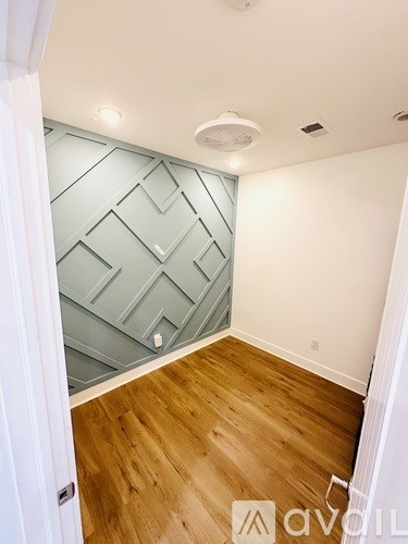 A room with wooden flooring and a geometric patterned wallpaper on the wall.