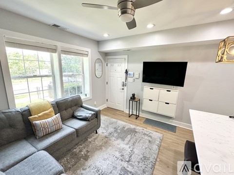 A living room with a grey couch and a flat screen TV mounted on the wall.