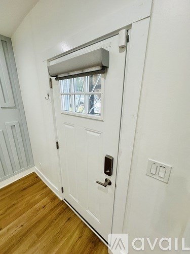 A white door with a window above it and a wooden floor.