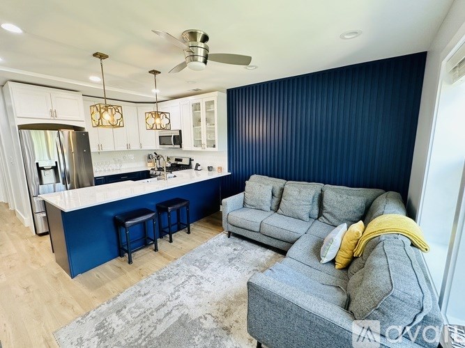 A modern kitchen with a bar area and a grey sofa with yellow pillows.