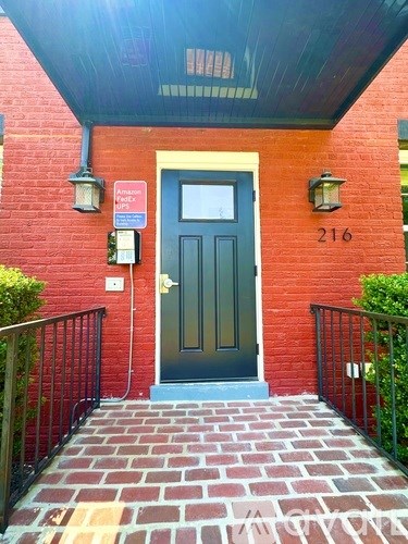 A red brick house with a black door and a sign on the wall.