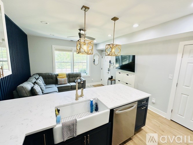 A modern kitchen with a large island and a living area with a grey sofa.
