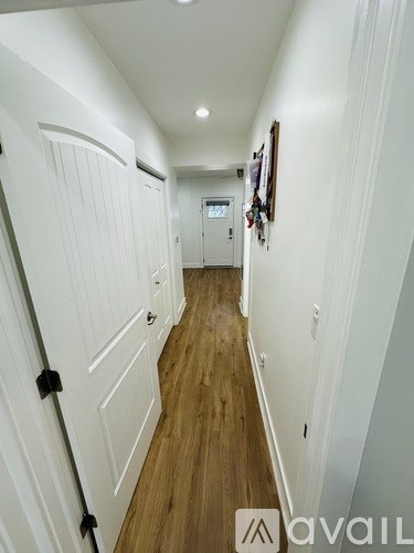A hallway with white walls and wood flooring.