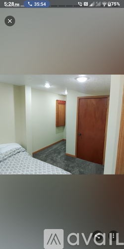 A bedroom with a bed, a door, and a wall-mounted light fixture.