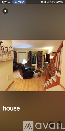 A living room with a staircase and a painting on the wall.