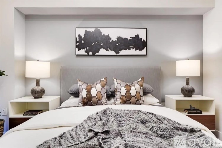 A bedroom with a large bed and a painting above it.