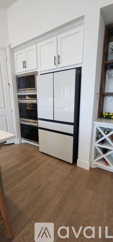 A kitchen with white cabinets and a black fridge.
