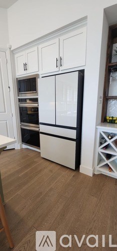 A kitchen with white cabinets and a black fridge.