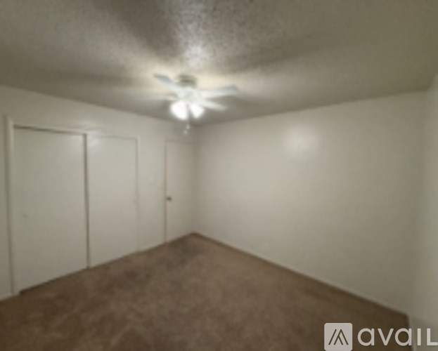 A room with a brown carpet and a ceiling fan.