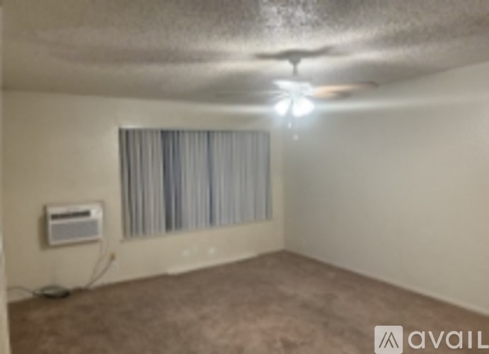 A room with a ceiling fan and a window with curtains.