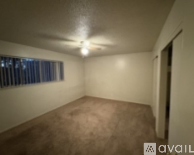 A room with a carpeted floor and a ceiling fan.