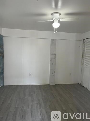 A room with a ceiling fan and wooden flooring.
