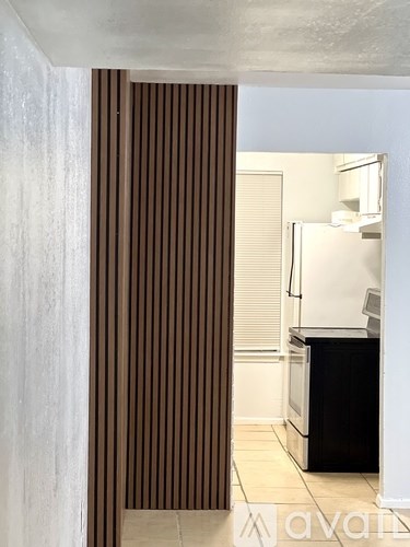 A kitchen with a black counter and brown striped curtains.