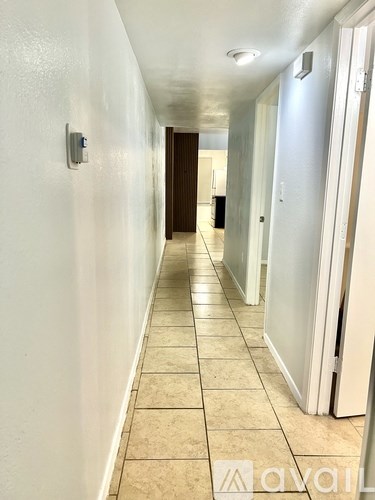 A long hallway with tiled floors and white walls.