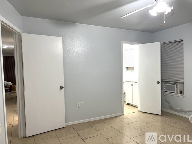 A room with white walls and a tiled floor with a door on the left and another door on the right.