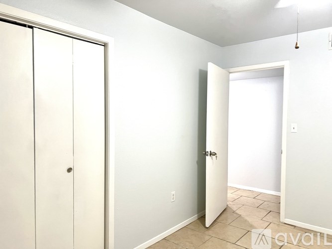 A white door with a silver handle is open in a room with white walls.