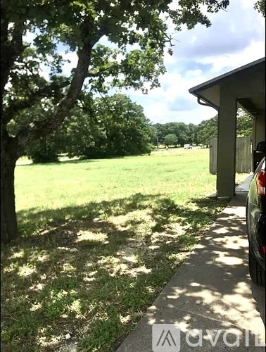 A car is parked on a concrete driveway leading to a house.