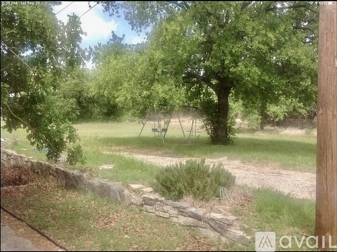 A grassy area with trees and a swing set.