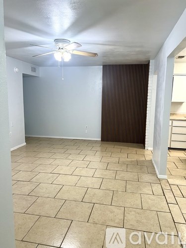 A room with a ceiling fan and tiled flooring.