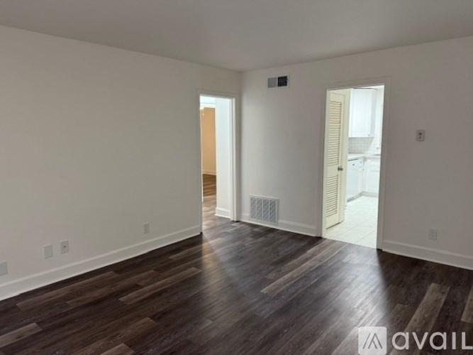 A room with wooden floors and white walls, with a door on the right side.