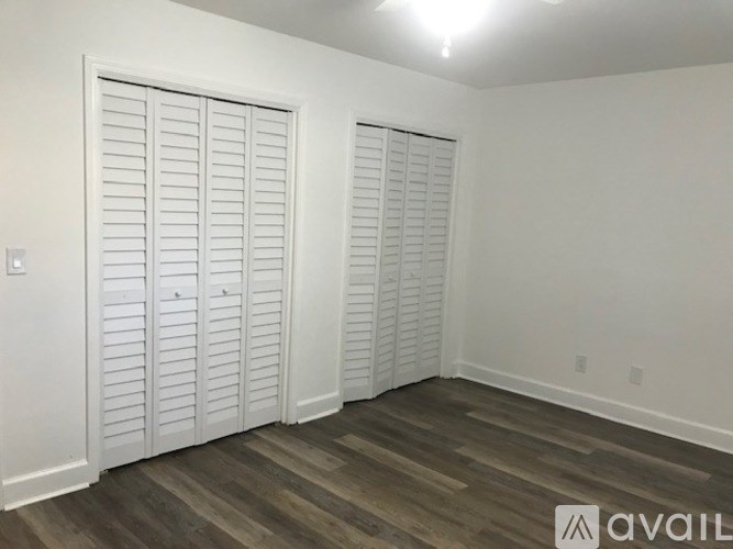 A room with two white closet doors and wooden flooring.