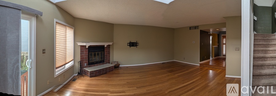 A spacious living room with a fireplace and a staircase.