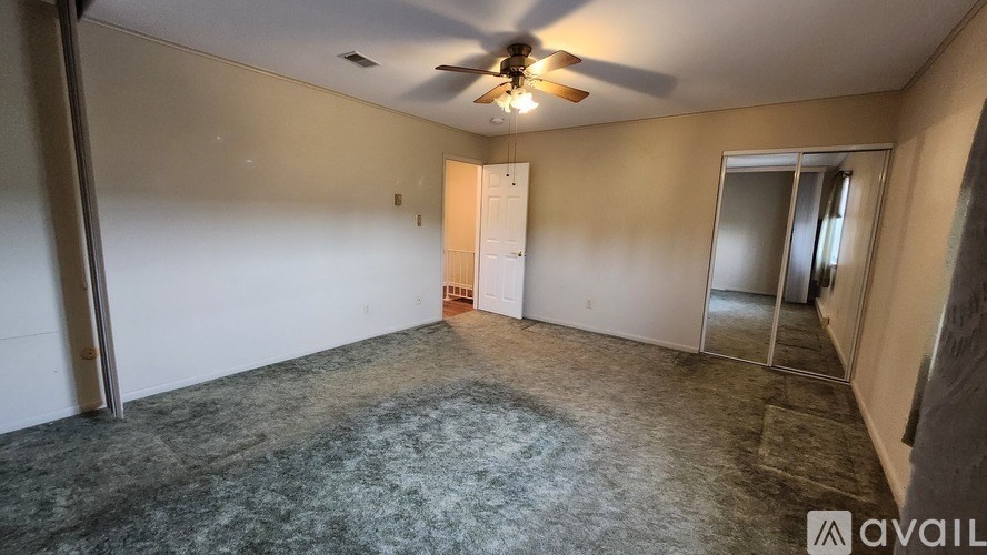 A room with a ceiling fan and a door in the middle.
