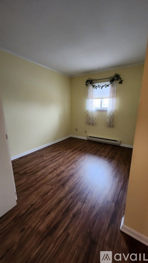A room with wooden floors and a window with a curtain.