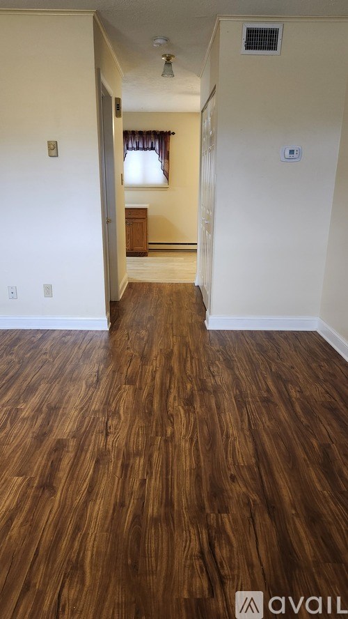 A hallway with wood flooring and a white wall.