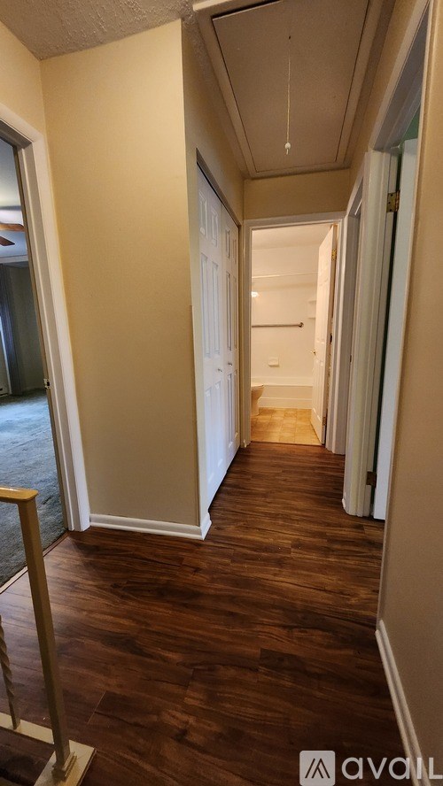 A hallway with wood flooring and white walls.