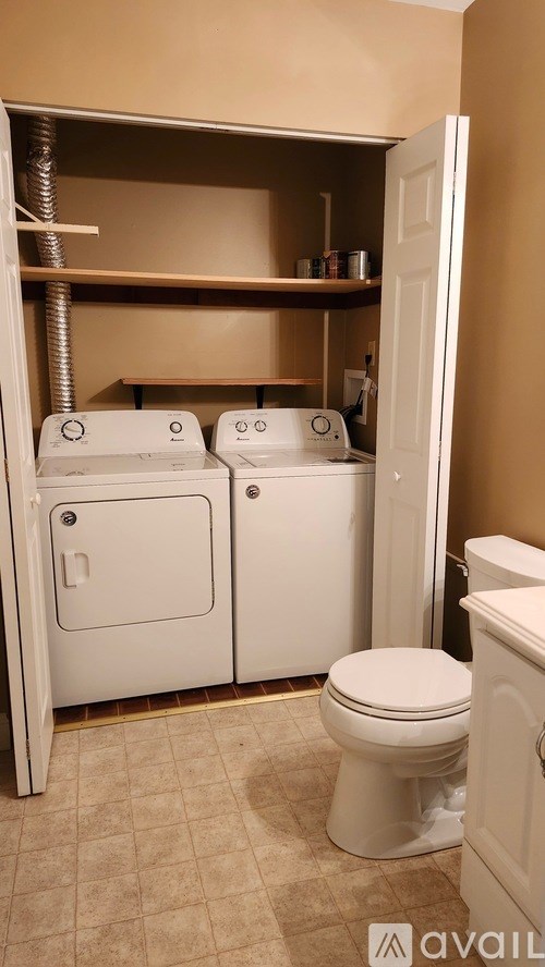 A white toilet is in a bathroom with a white cabinet and a white door.