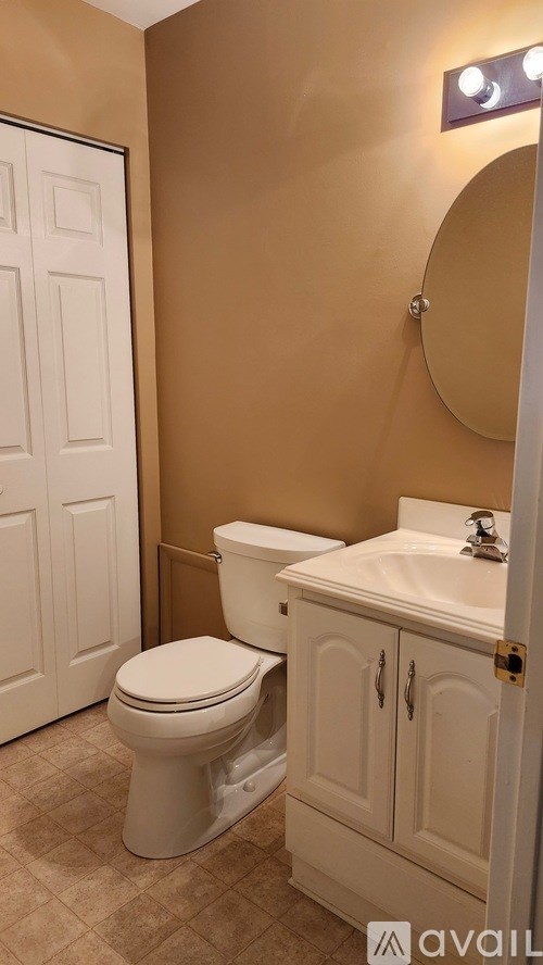 A bathroom with a toilet, sink and mirror.