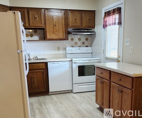 A kitchen with white appliances and wooden cabinets.