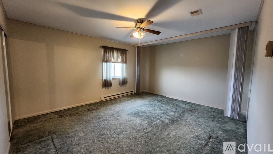 A room with a ceiling fan and carpeted floor.
