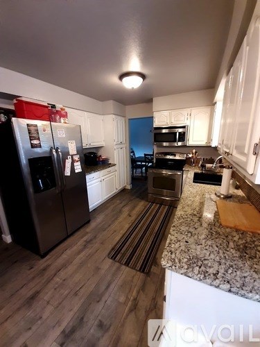 A kitchen with a refrigerator, microwave, oven, and sink.
