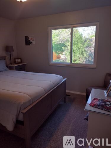 A bedroom with a bed, nightstand, and window.