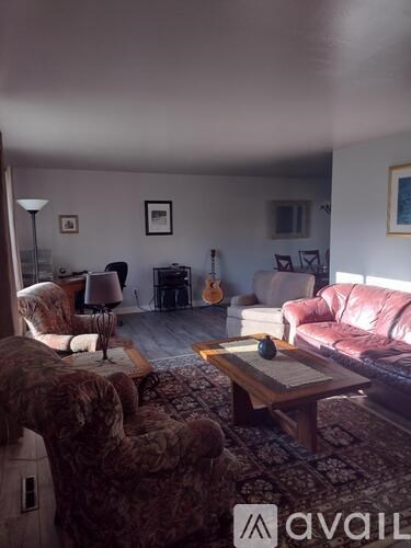 A living room with a couch, chair, and guitar.