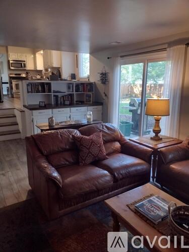 A brown leather couch with a pillow and a book on it.