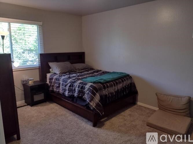 A bedroom with a bed, a chair, and a window.