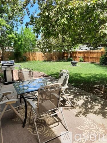 A glass table with metal chairs is set up on a patio.