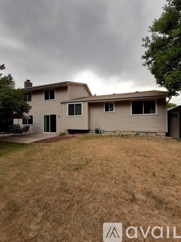 A house with a brown lawn and a cloudy sky in the background.
