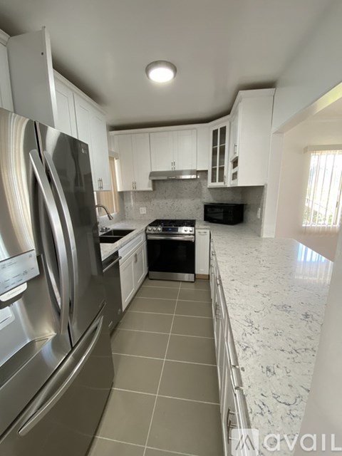 A kitchen with a stainless steel refrigerator and a white countertop.