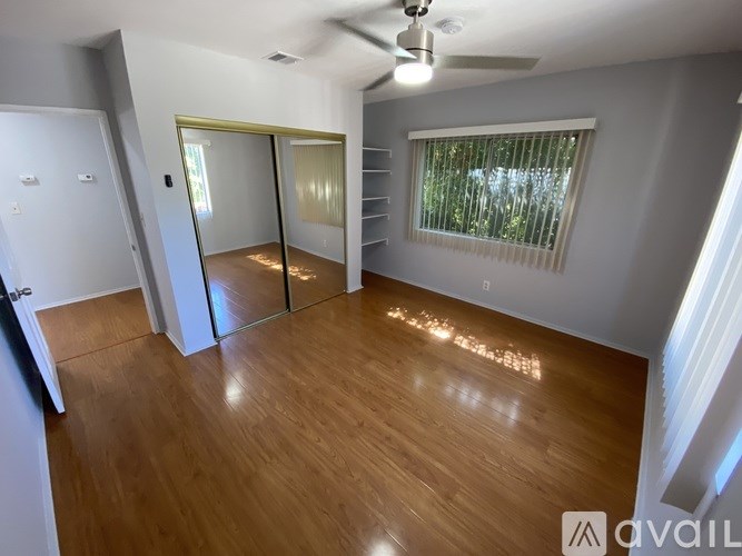 A room with a ceiling fan and sliding glass doors.