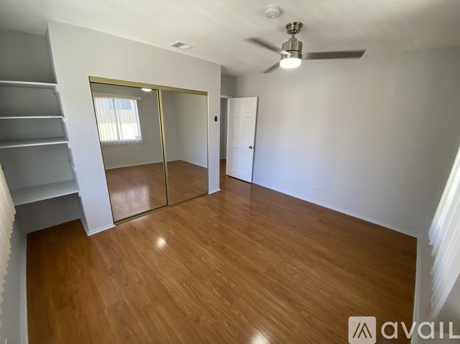 A room with wooden flooring and a ceiling fan.
