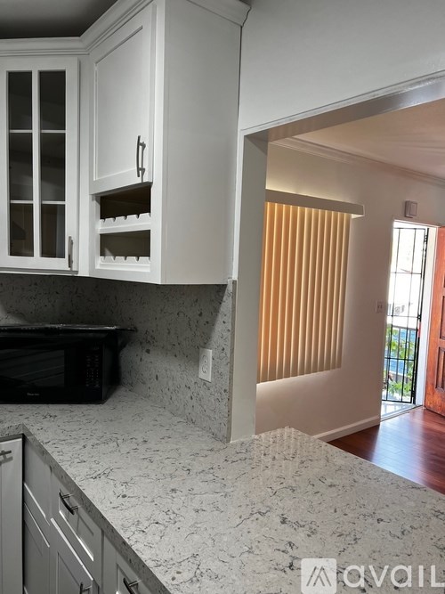 A kitchen with white cabinets and a black microwave.
