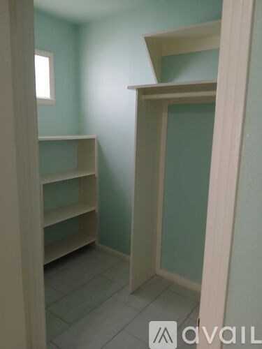 A room with a shelving unit and a window.